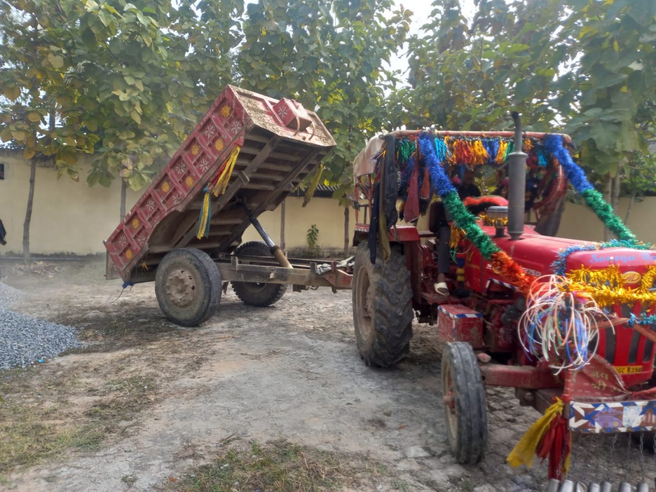Un tracteur décoré de guirlandes multicolores vide une benne de graviers sur le site du futur home pour seniors
