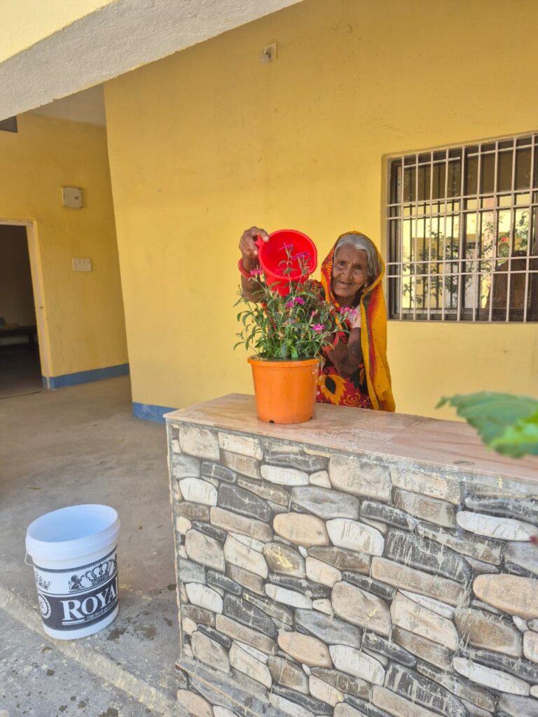 Vie quotidienne dans le refuge : une femme âgée arrose une plante.